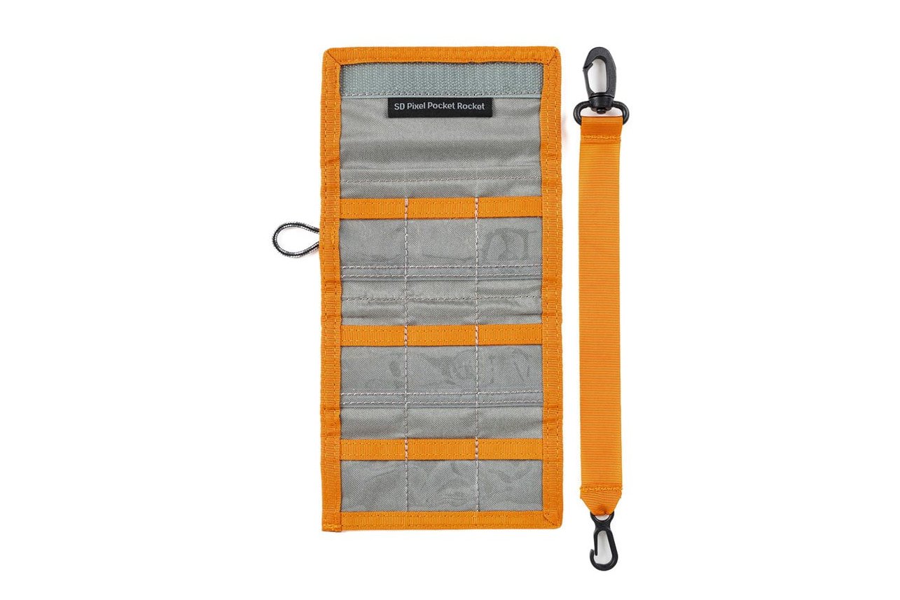Orange and gray SD card organizer with an accompanying orange strap with hooks.