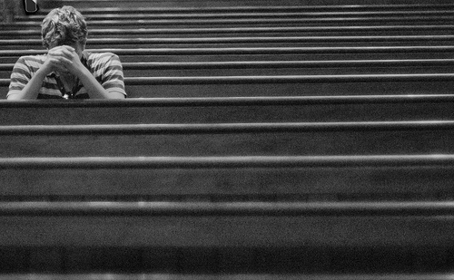 young-man-praying-in-one-of-several-rows-of-pews.jpg