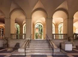 Archways and stairs leading to a garden view in a classical building.