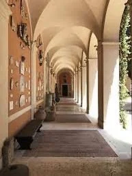 A covered outdoor walkway with archways, potted plants, and bench seating.
