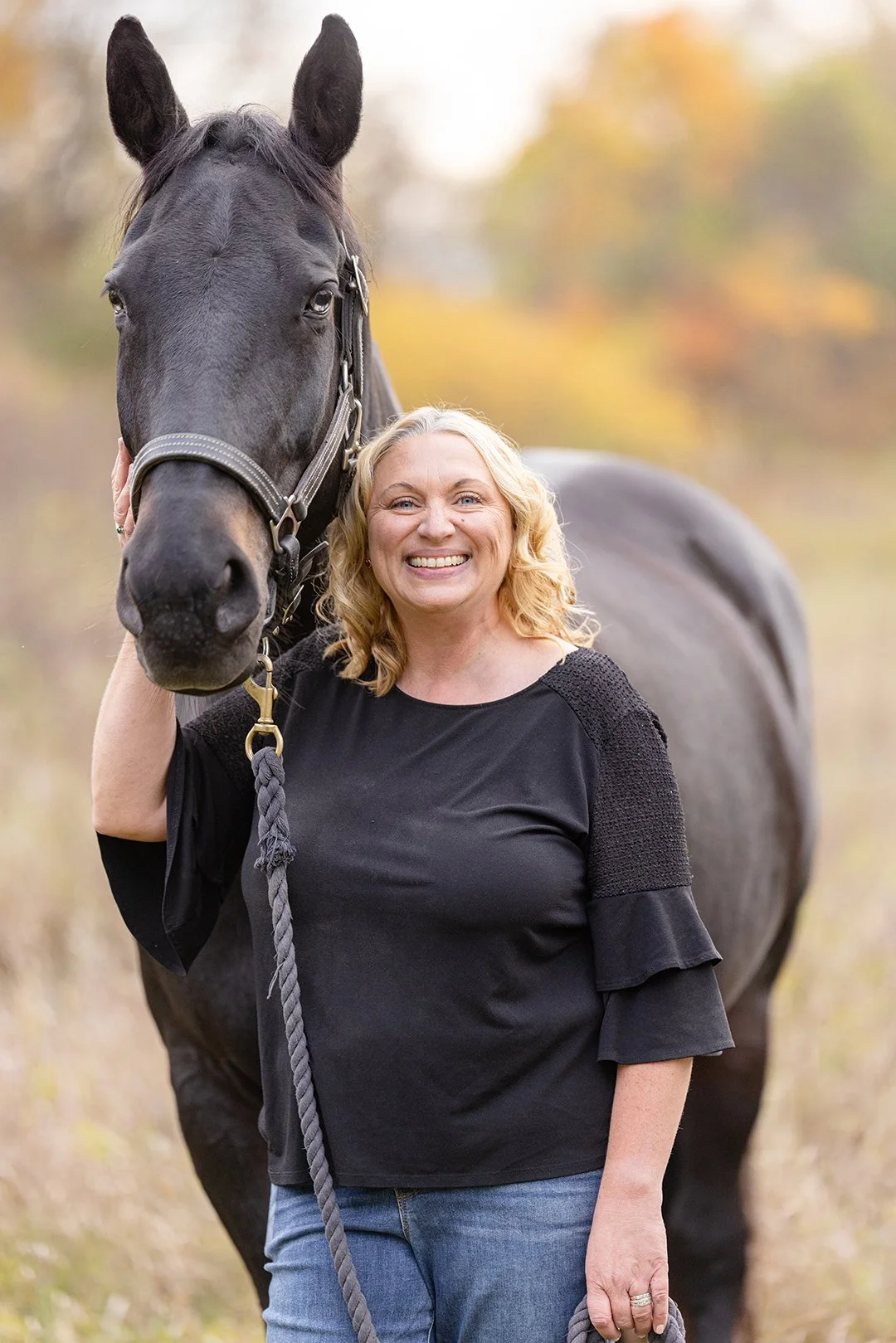 An intimate close-up showing Julie and her black dressage horse cheek to cheek during a horse and rider portrait session in Wisconsin.