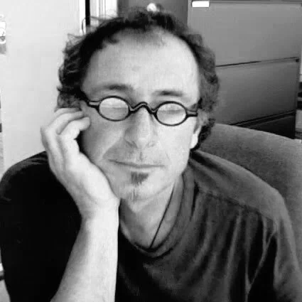 headshot of man with oval spectacles