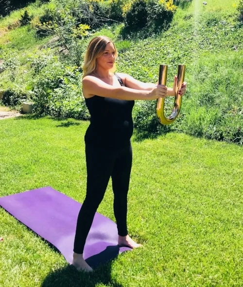 TADASANA (Mountain Pose) with Core Stabilization : Stand with feet a bit wider than your hips. Hold the Ubarre out in front of you. Relax your shoulders down. Hug your biceps to your triceps. Release your tailbone down as you gently hug baby toward your midline. 