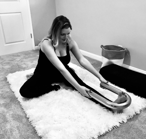 JANU SIRSANA (One-Legged Forward Fold): Sit on a folded blanket with your legs directly out in front of you and toes pointed toward the sky (Dandasana). Using your hands, draw one leg in toward you and rest the bottom of your foot against your inner thigh as your knee relaxes down. Hold the Ubarre with both hands and place the rounded end around your flexed foot. Fold forward to the extent that baby will allow. Bend your extended leg if needed. 