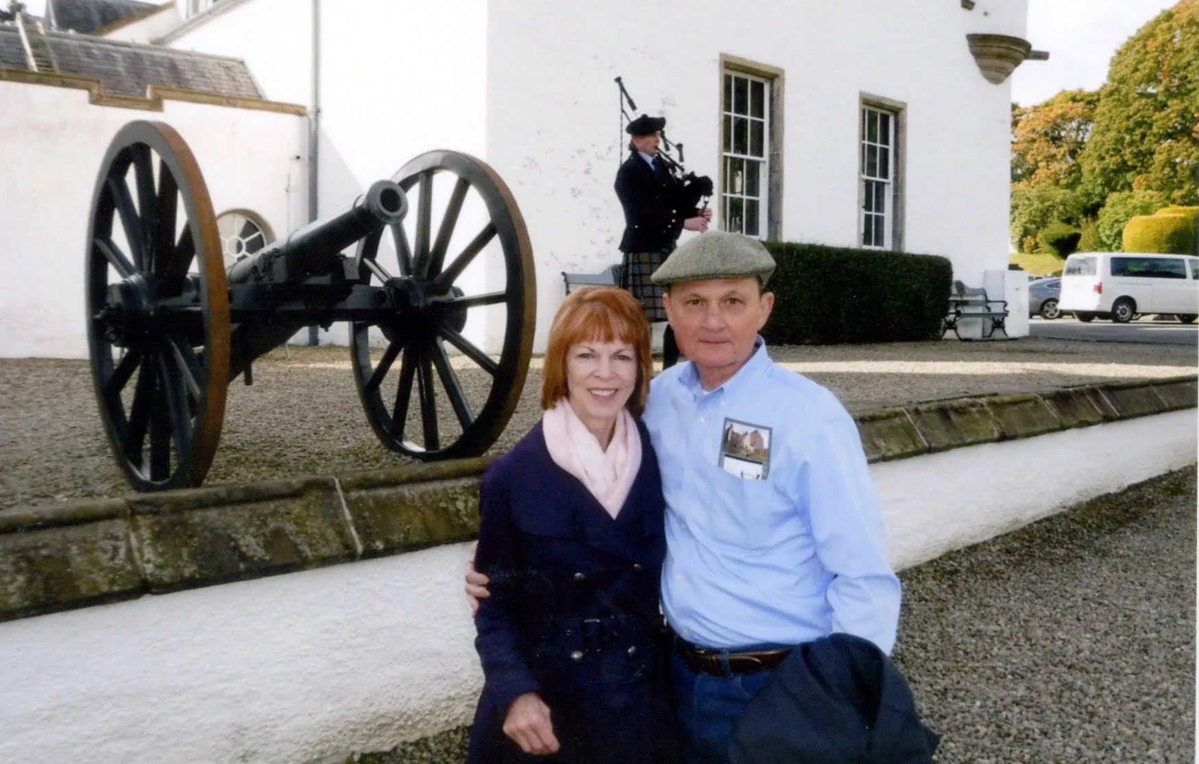 ^ Carolyn and Jim stand outside of Blair Castle in Scotland while listening to the bagpiper in September 2016. 