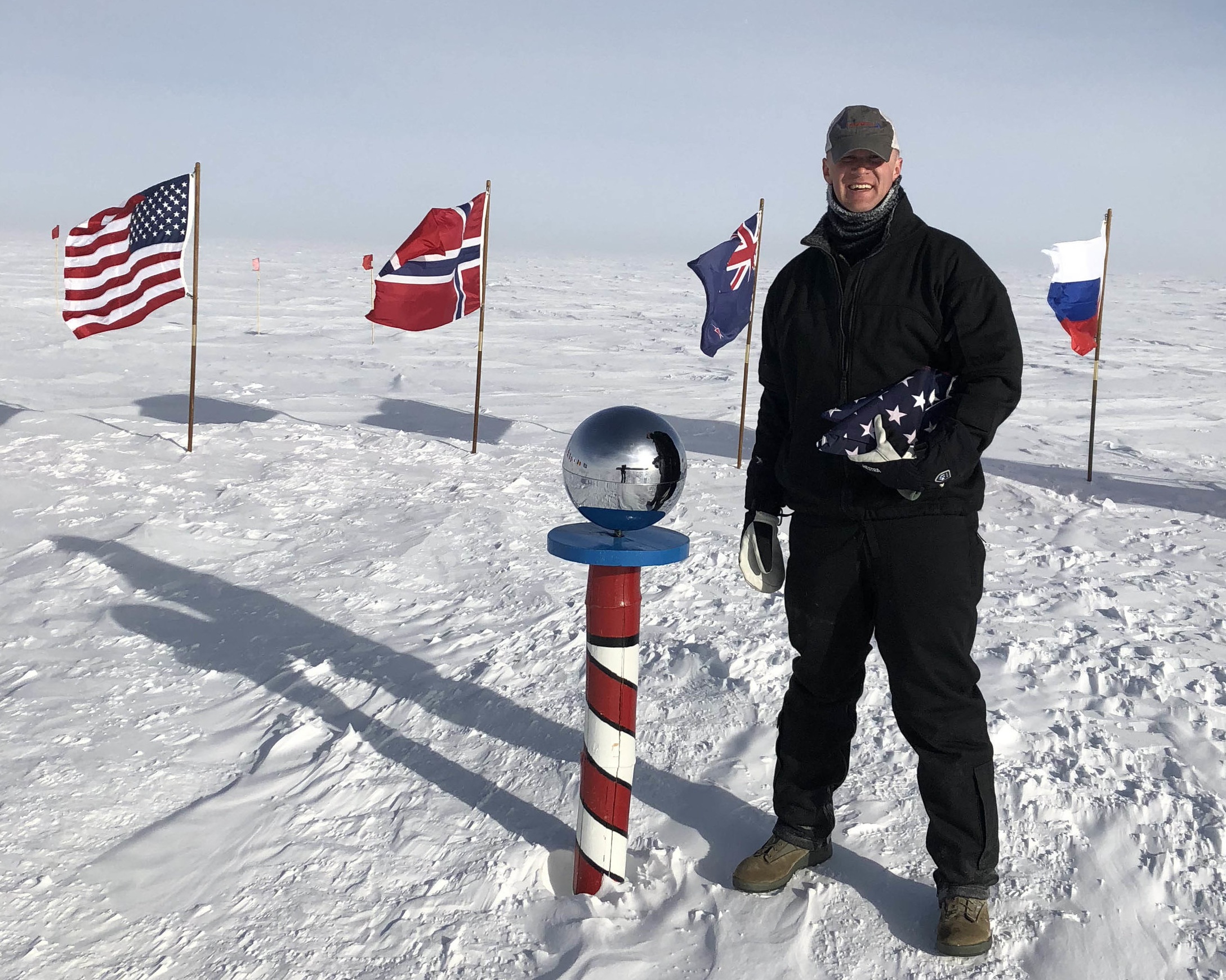 Matt at the South Pole preparing to aeromedically evacuate a patient who had high altitude pulmonary edema (HAPE) and was not stable enough to stay at South Pole Station. He is holding the American Flag that he flies in the backs of the aircraft in which he moves patients. This flag has traveled over the skies of southwest Asia, north Africa, South America, North America, the islands of the Pacific and Antarctica.