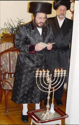 hanukkah biala rebbe lights the menorah.png