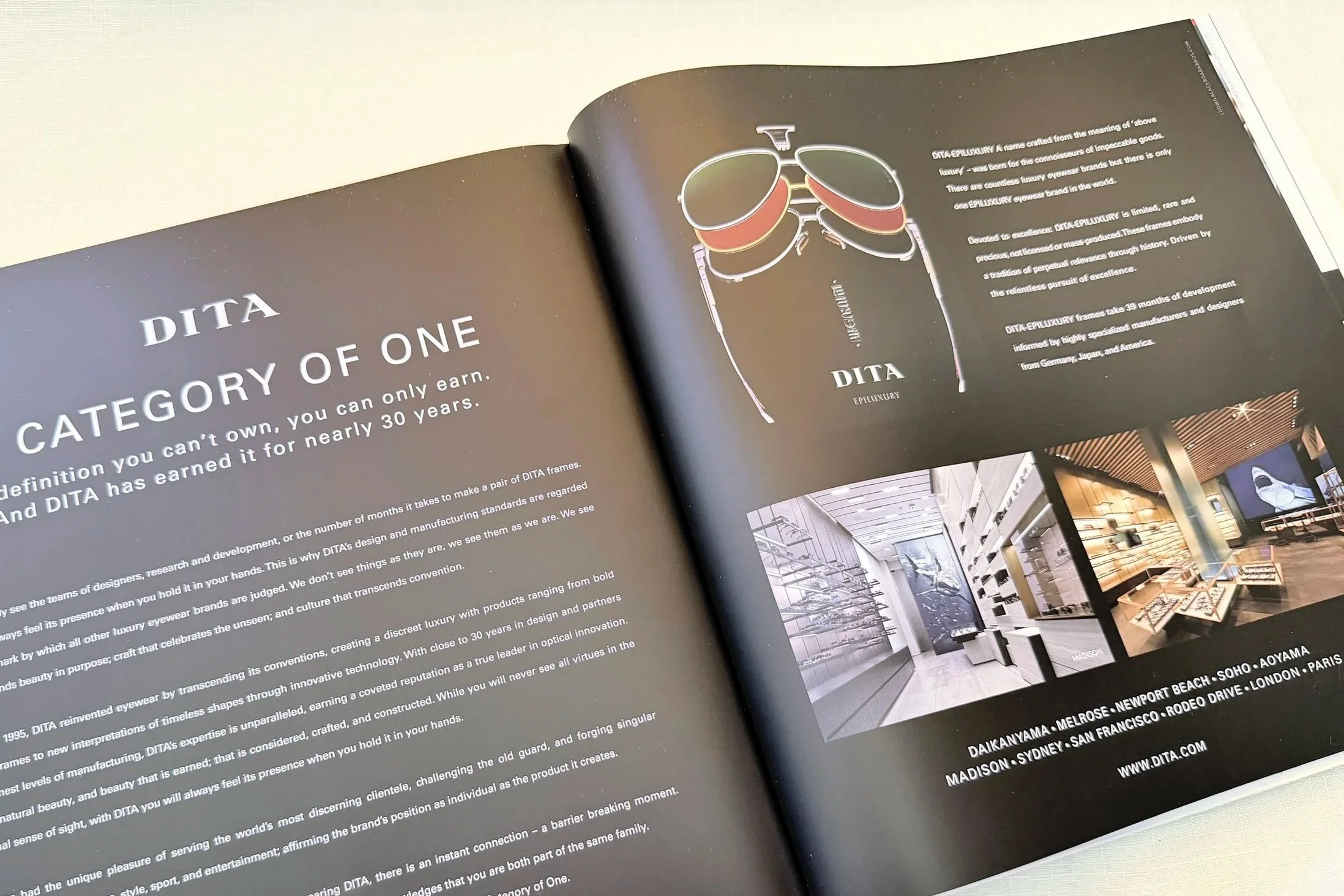 An open magazine or brochure showing a section about DITA eyewear brand with images of glasses, a modern interior space of a store, and text describing the brand's luxury and craftsmanship.