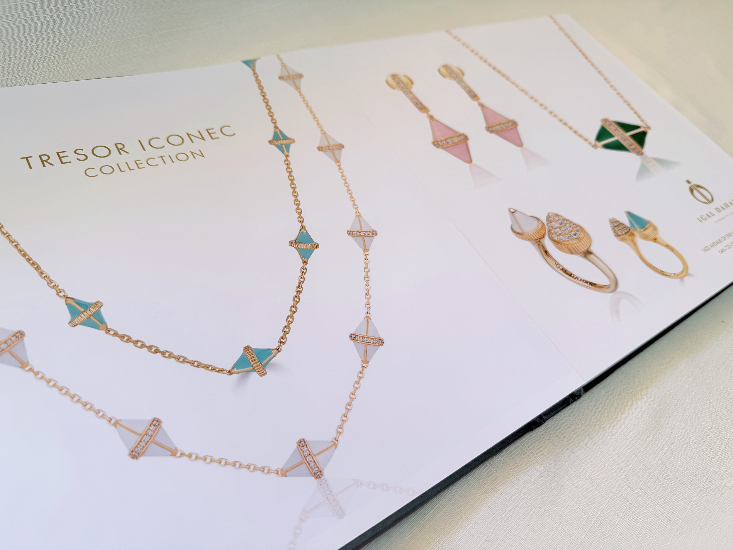 Gold jewelry including necklaces and rings displayed on a white surface, with a jewelry collection label.