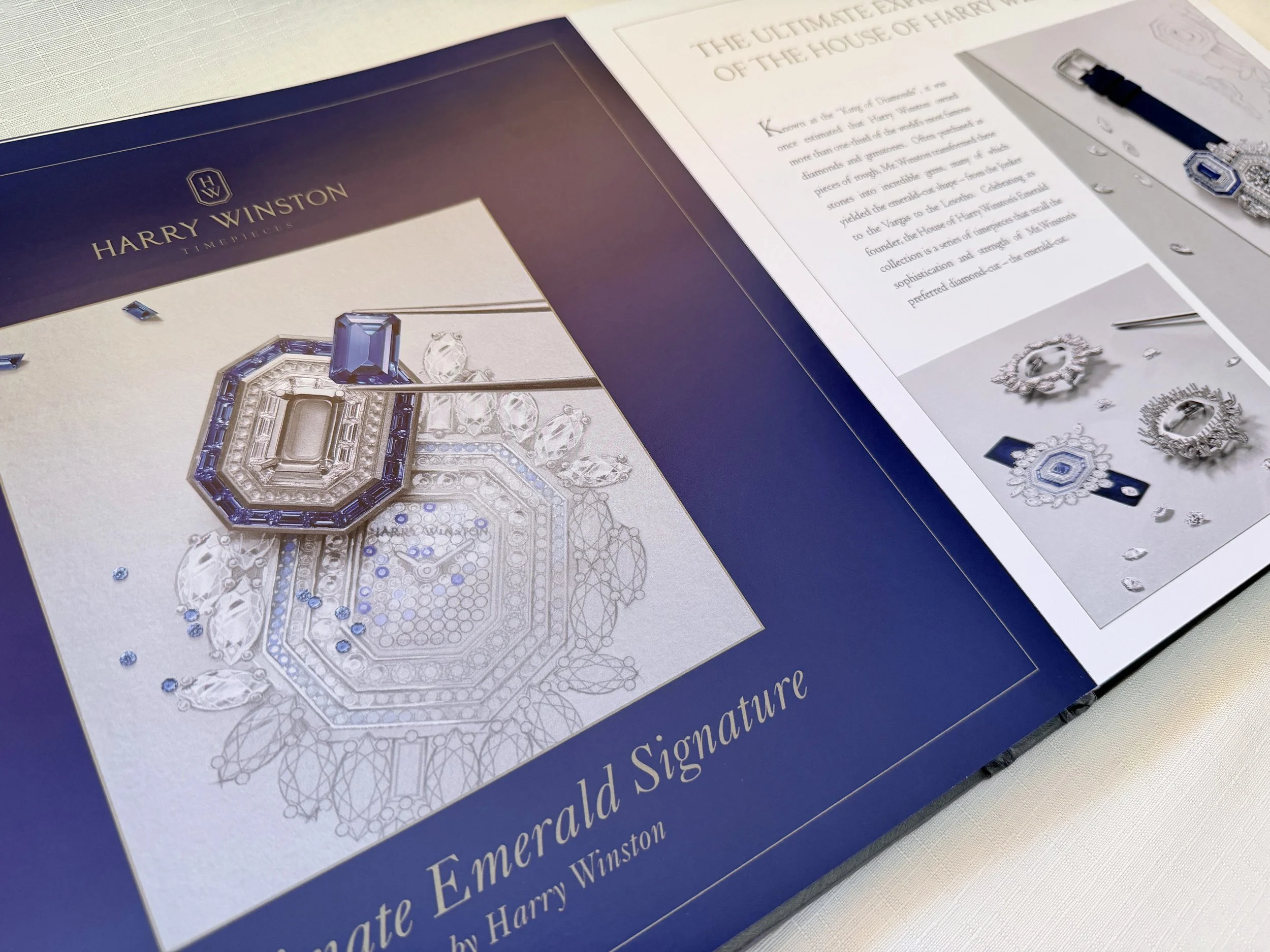 A book displaying Harry Winston jewelry, featuring a large, intricate ring with blue and clear gemstones, surrounded by smaller jewelry images and descriptive text.