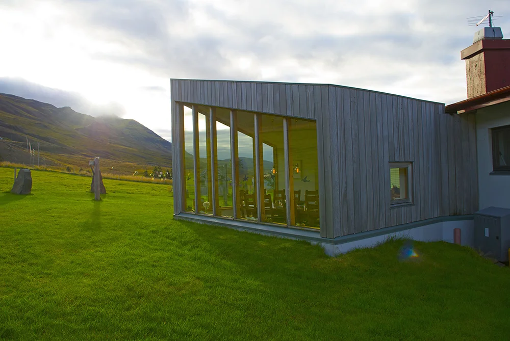 Modern retreat lodge surrounded by mountains, offering comfort and reflection during a spiritual Ashram retreat in Iceland.