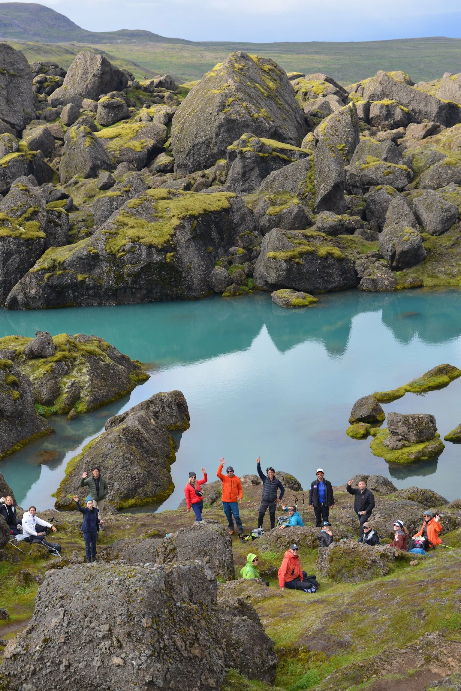 Hiking group resting by a turquoise glacial pool in Iceland, showcasing some of the best treks in Iceland.