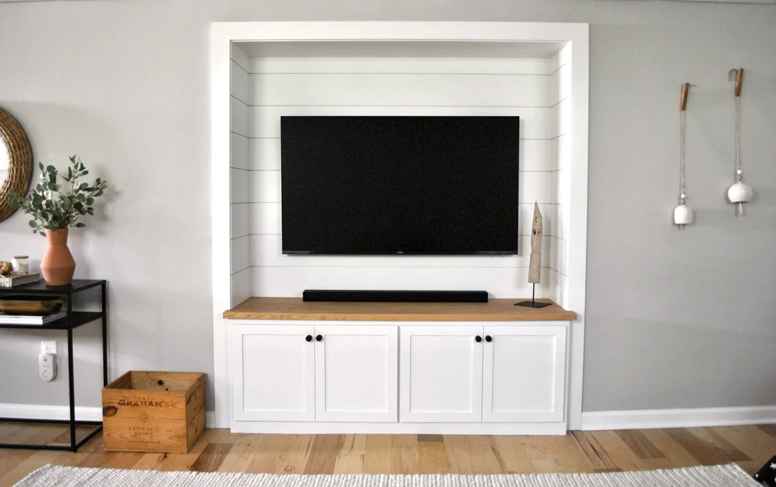 Basement built in with shiplap paneling, white shaker cabinetry, and matte black hardware perfect for a big tv and lots of toy storage below.