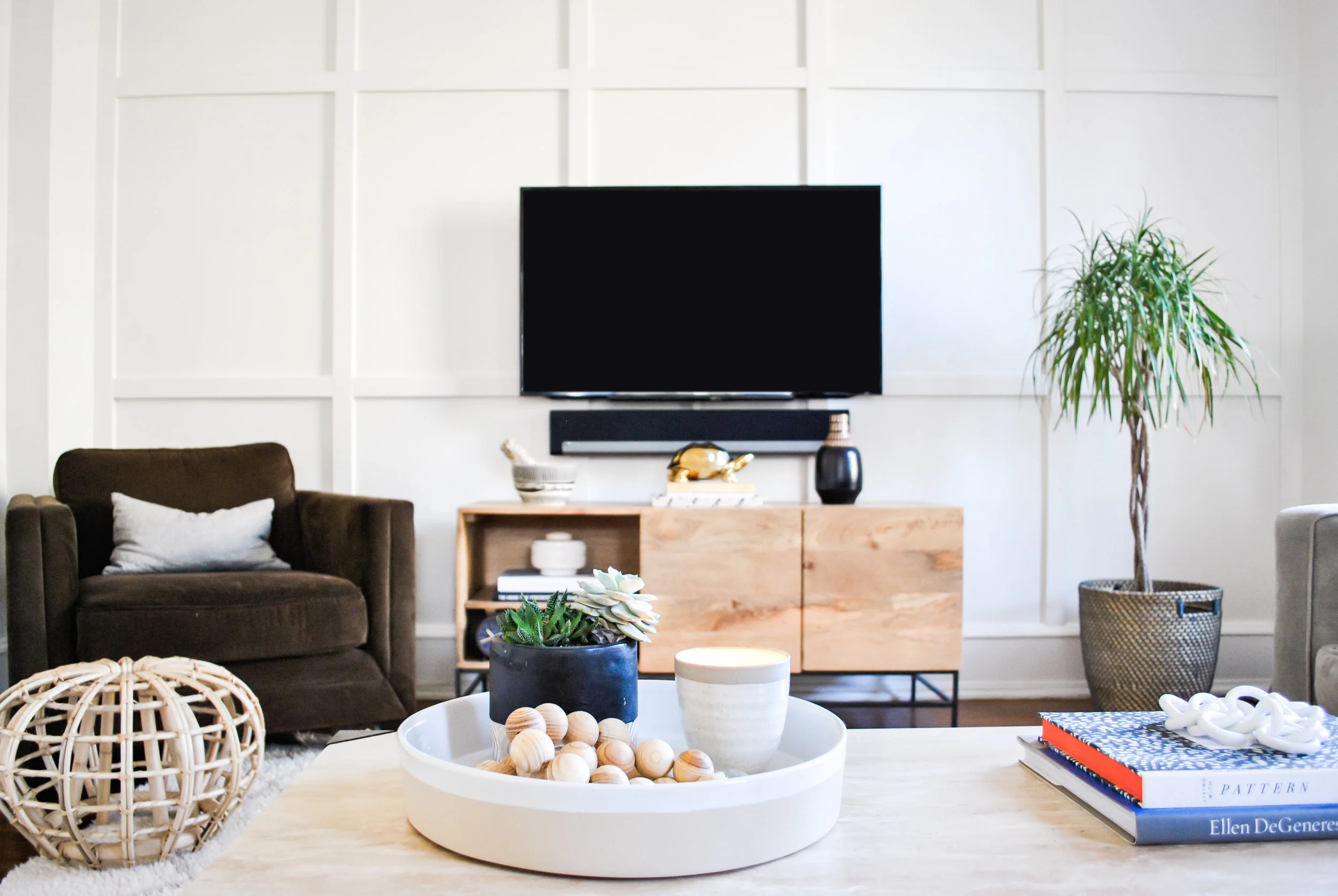 Light and bright living room painted Benjamin Moore Classic Gray, with focal wall, rattan ottoman, succulents and reclaimed wood media center | Sharp + grey Interiors