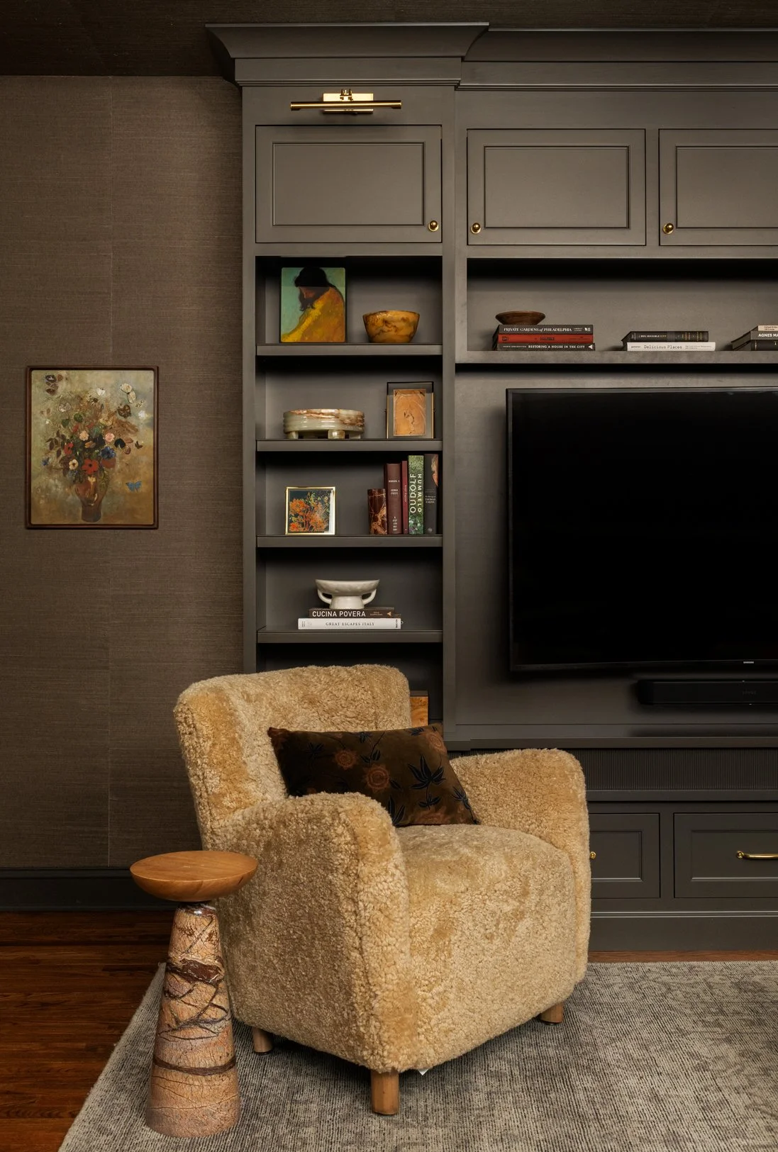 Parisian style living room with dark paint custom cabinet built ins, upholstered accent chair and antique rug with modern stone and wood drink table