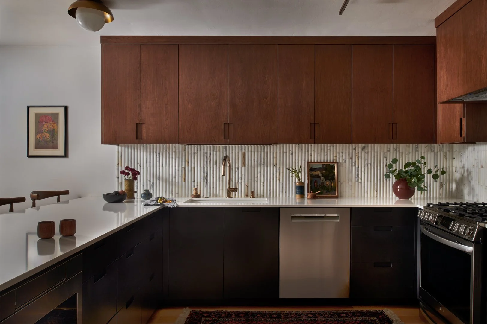Walnut wood kitchen cabinets in a modern home with reeded tile backsplash and modern appliances with dark contrasting lower cabinets