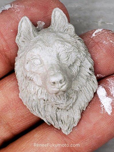 wolf portrait ceramic sculpture pendant front view renee fukumoto on fingers.jpg