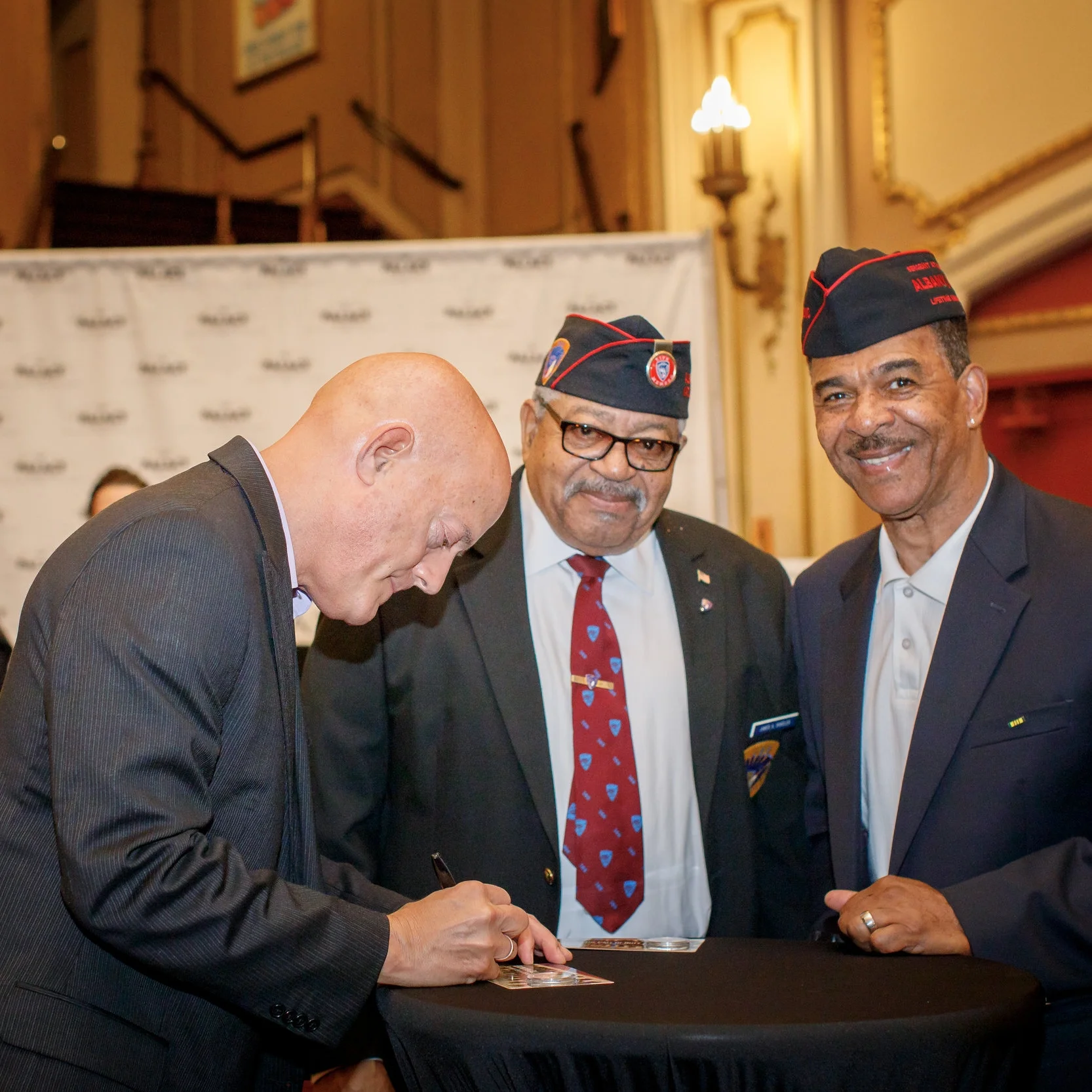 Artist Chris Costello signs medals for Veterans of the 369th Regiment.