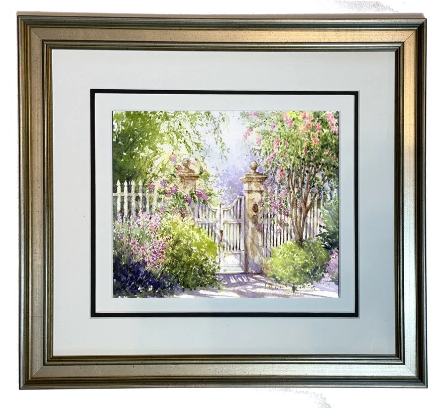  A picturesque white picket fence stands in front of an elusive Charleston Garden. The welcoming gate is adorned with lush vines which create a canopy of delicate pink and lavender flowers. The vibrate greenery and new growth are alive with the promi
