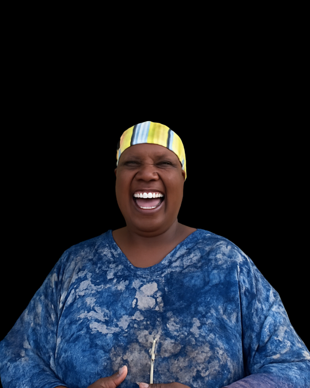 A woman with a yellow and blue striped head wrap, wearing a blue tie-dye shirt, smiling and laughing with her mouth open, holding a matchstick, against a black background.
