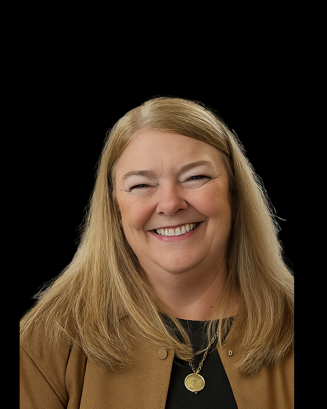 A middle-aged woman with long blonde hair smiling against a black background, wearing a tan blazer and a gold necklace.