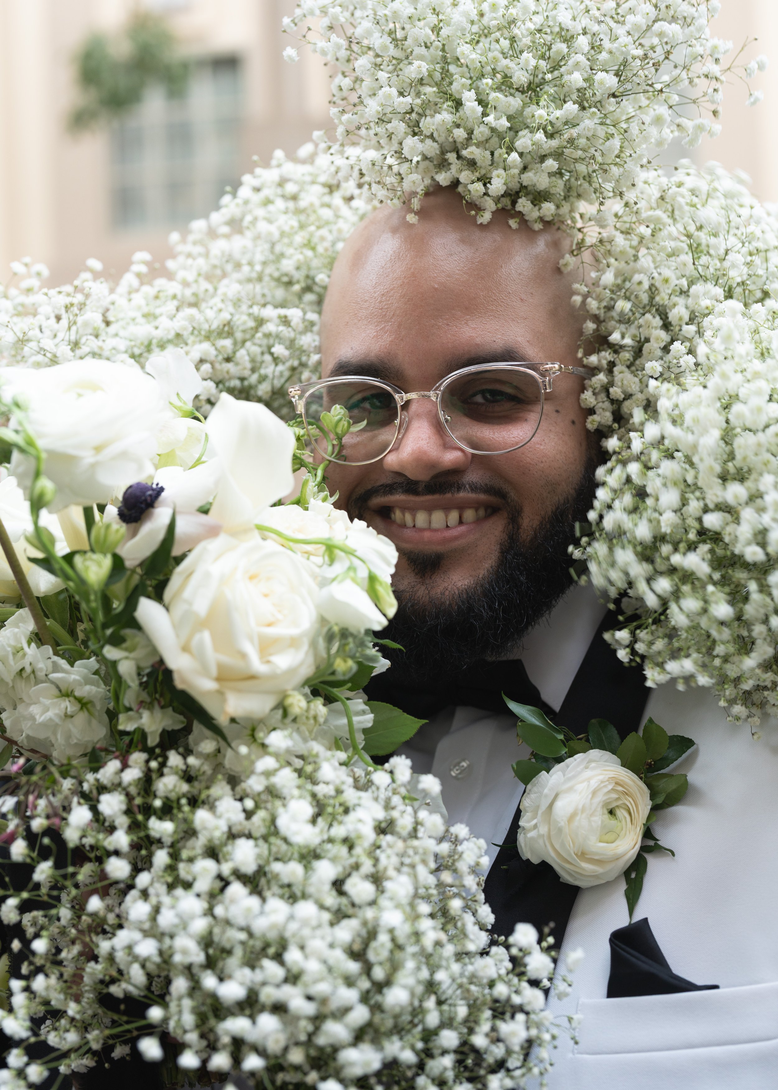 The groom surrounding by floral arrangements from his groomsmen. Timeless wedding photography in Darien, CT.