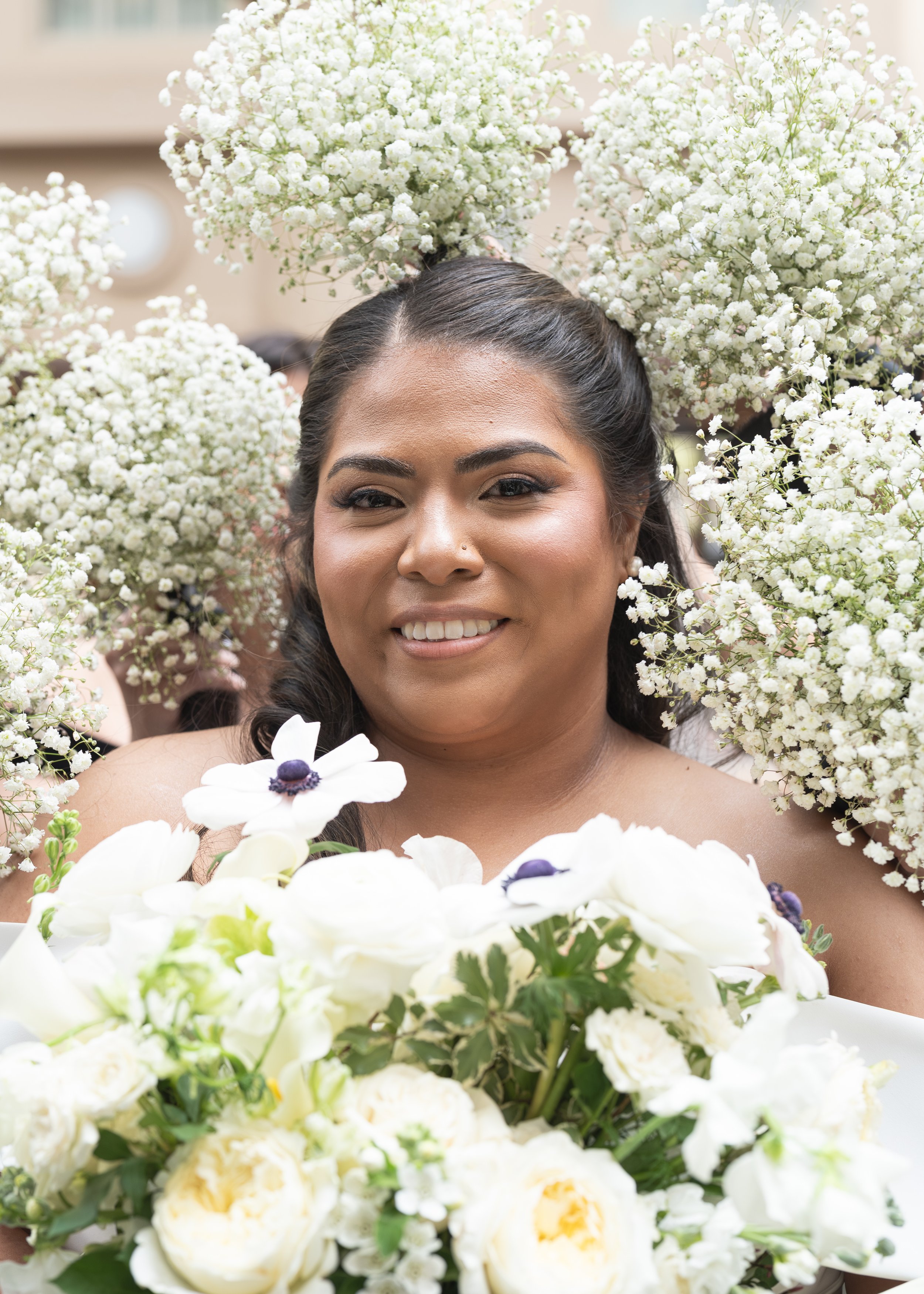 A newlywed bride surrounding by floral arrangements by her bridesmaids. Cherished wedding photography in Darien, CT.