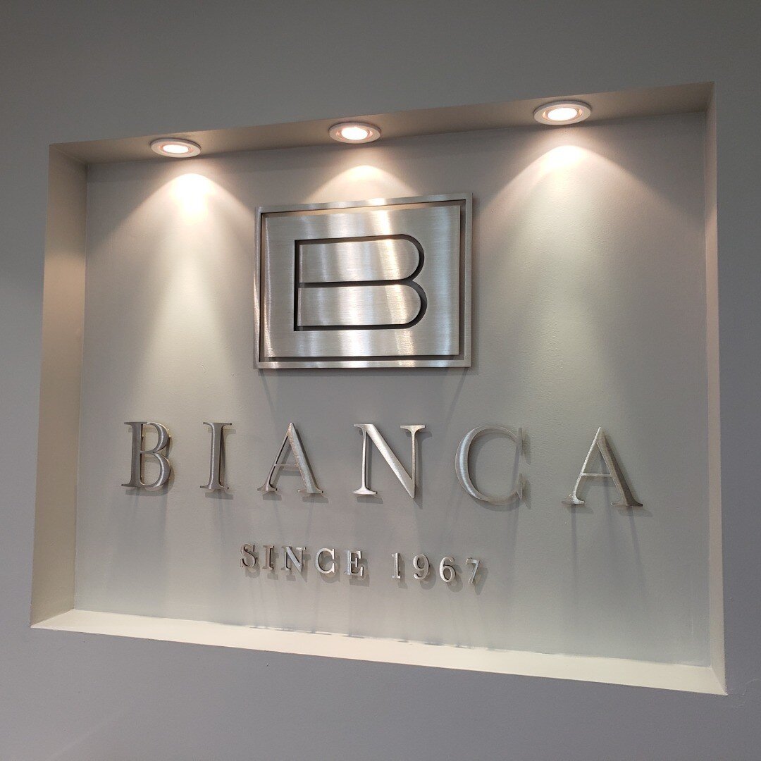 custom waterjet cut out 1/4&quot; thick brushed satin silver stainless steel metal letters/logo pin-mounted to interior recessed wall niche, floating off with 1/2&quot; spacers. #interiors #officeinteriors #corporateinteriors #interiordesign #commerc