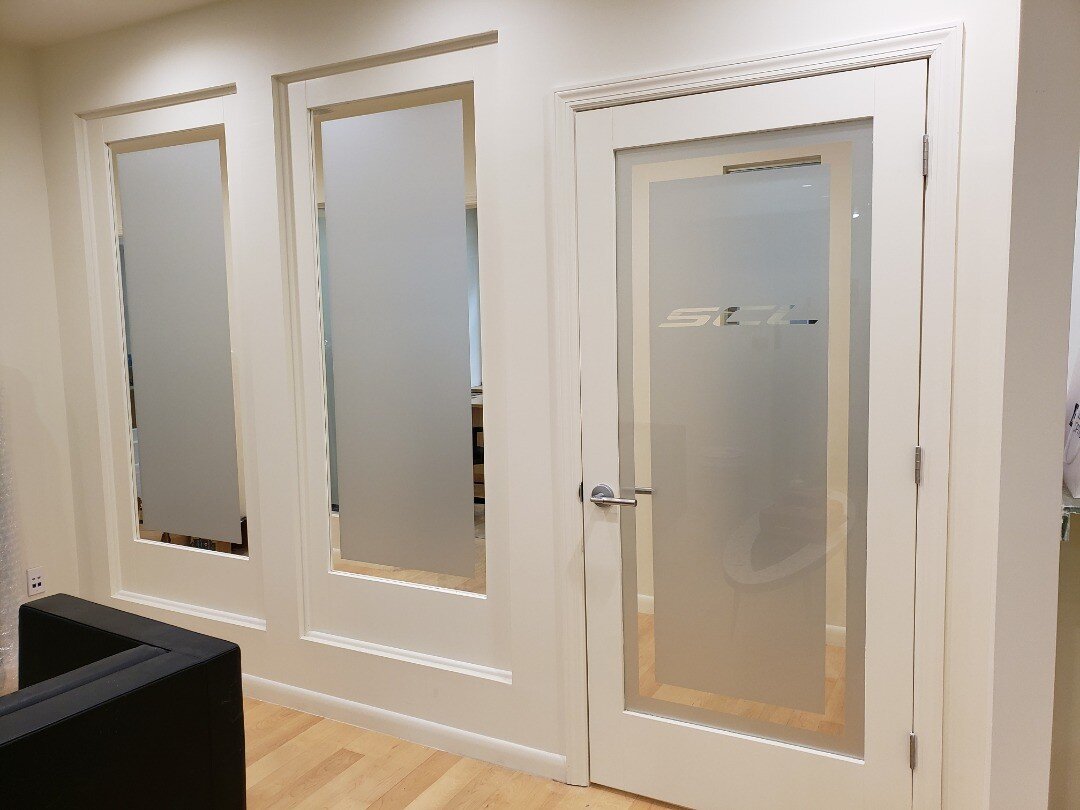 frosted film / etch vinyl privacy glass covering for office/showroom glass doors with logo drop-out in clear and clear border. #interiors #officeinteriors #corporateinteriors #interiordesign #commercialdesign #commercialinteriordesign #lobbydesign #o