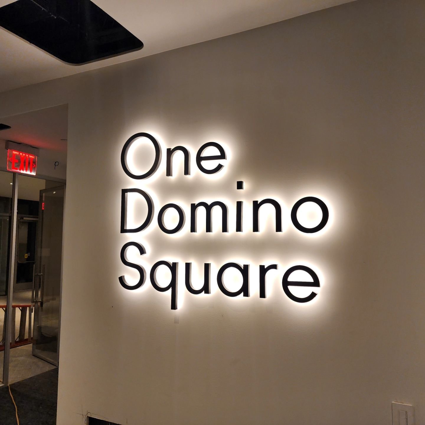 Custom Fabricated 3d backlit metal logo / letters painted black with warm white leds behind for backlit illumination installed interior lobby of hi-rise luxury apartment building in DUMBO Brooklyn.