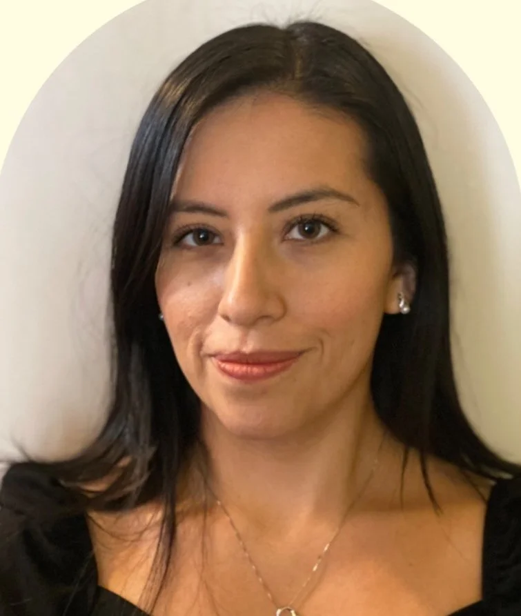 A woman with shoulder-length dark hair, wearing earrings and a necklace, smiling while lying down against a light background.