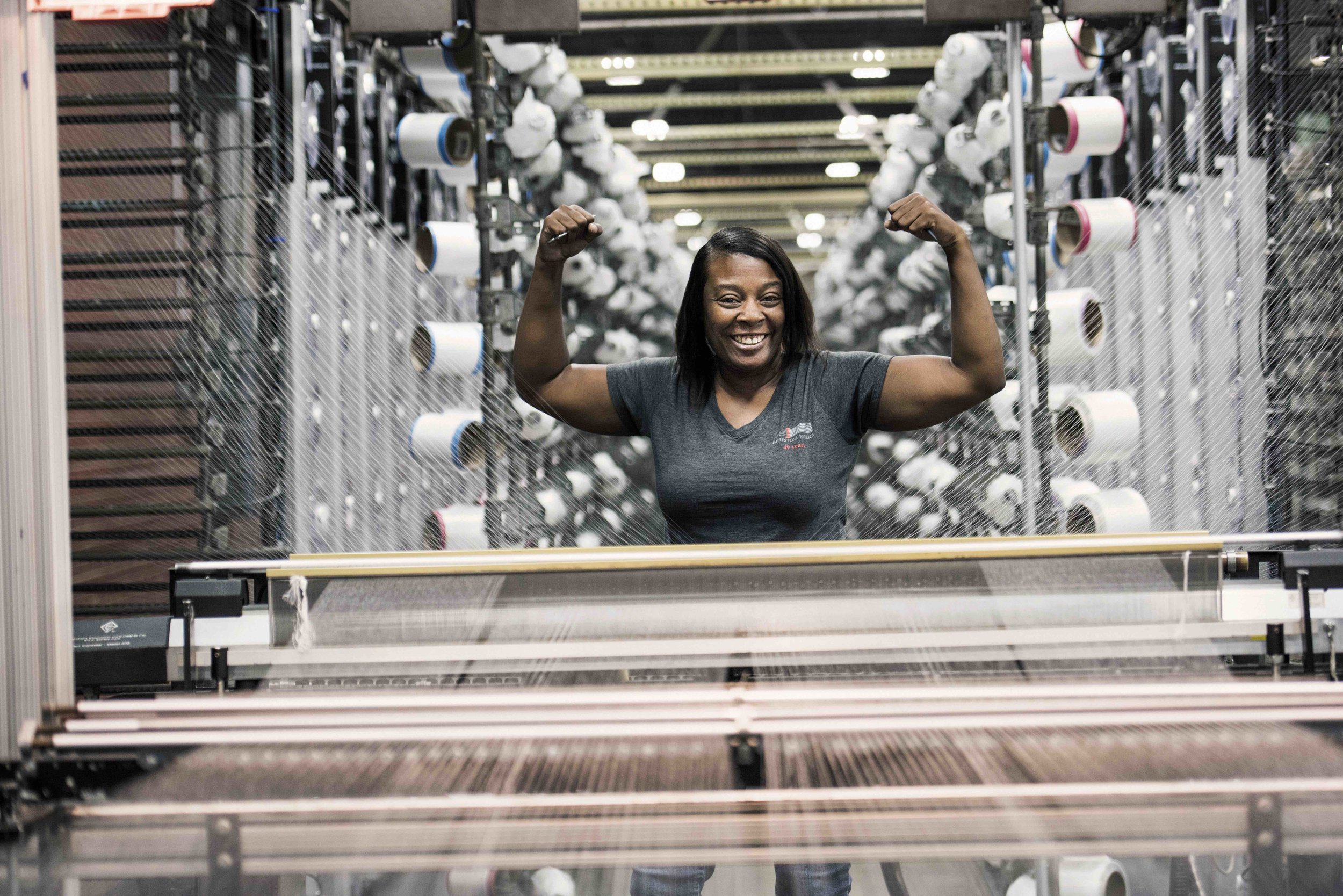 Fairystone Fabrics employee smiling beside factory equipment