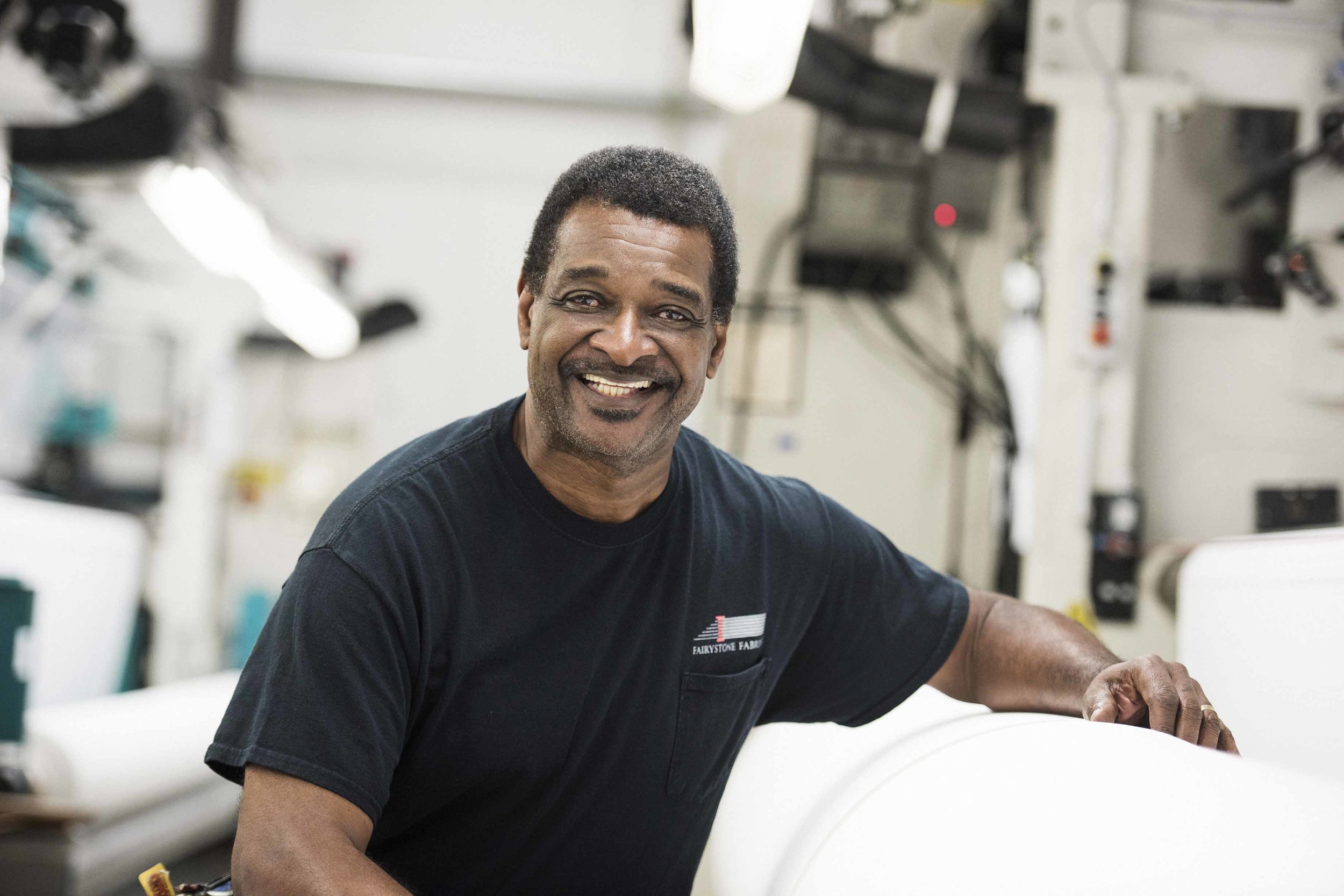 Fairystone Fabrics employee smiling beside factory equipment