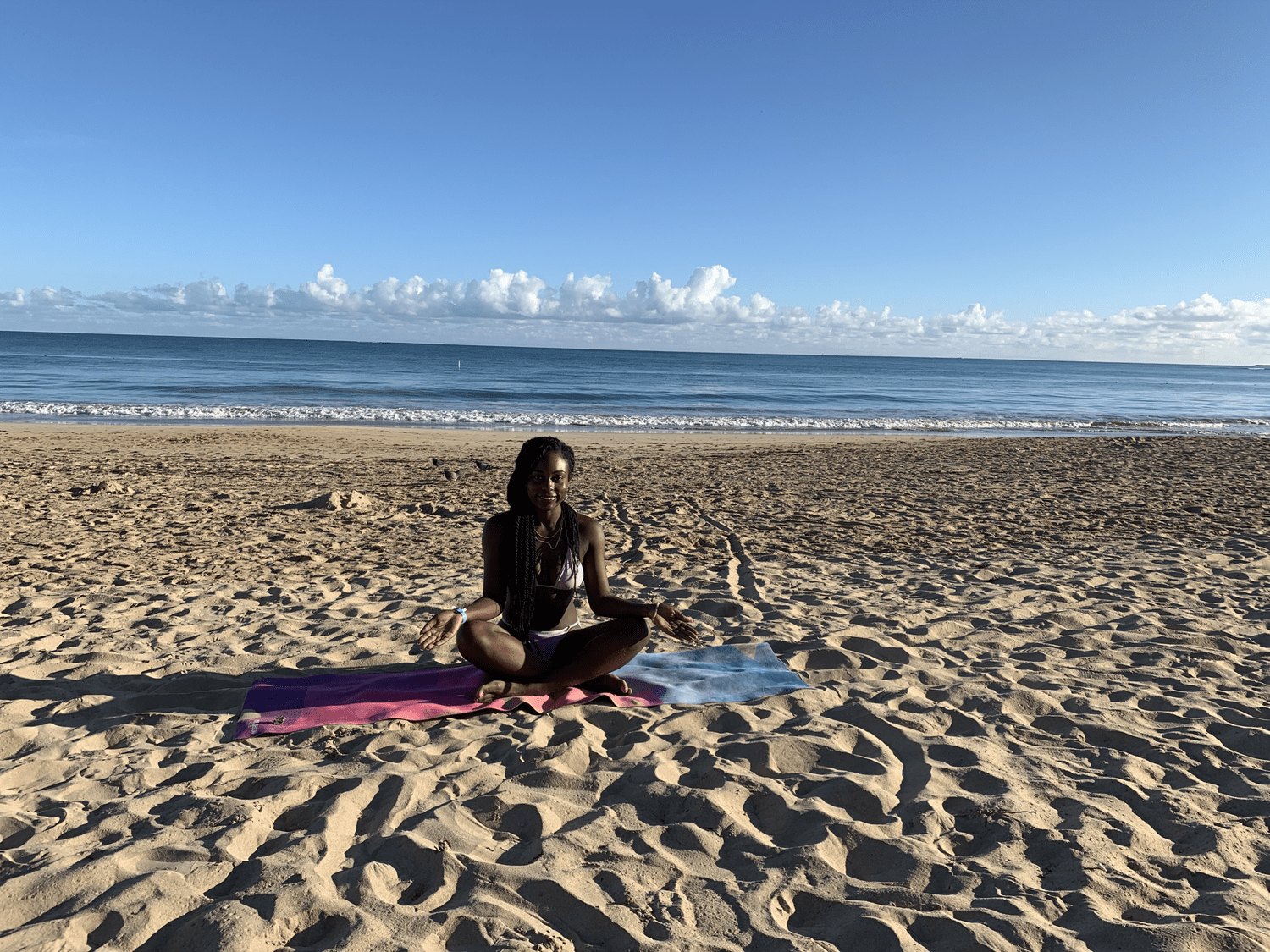 Brielle meditating on the beach by the ocean