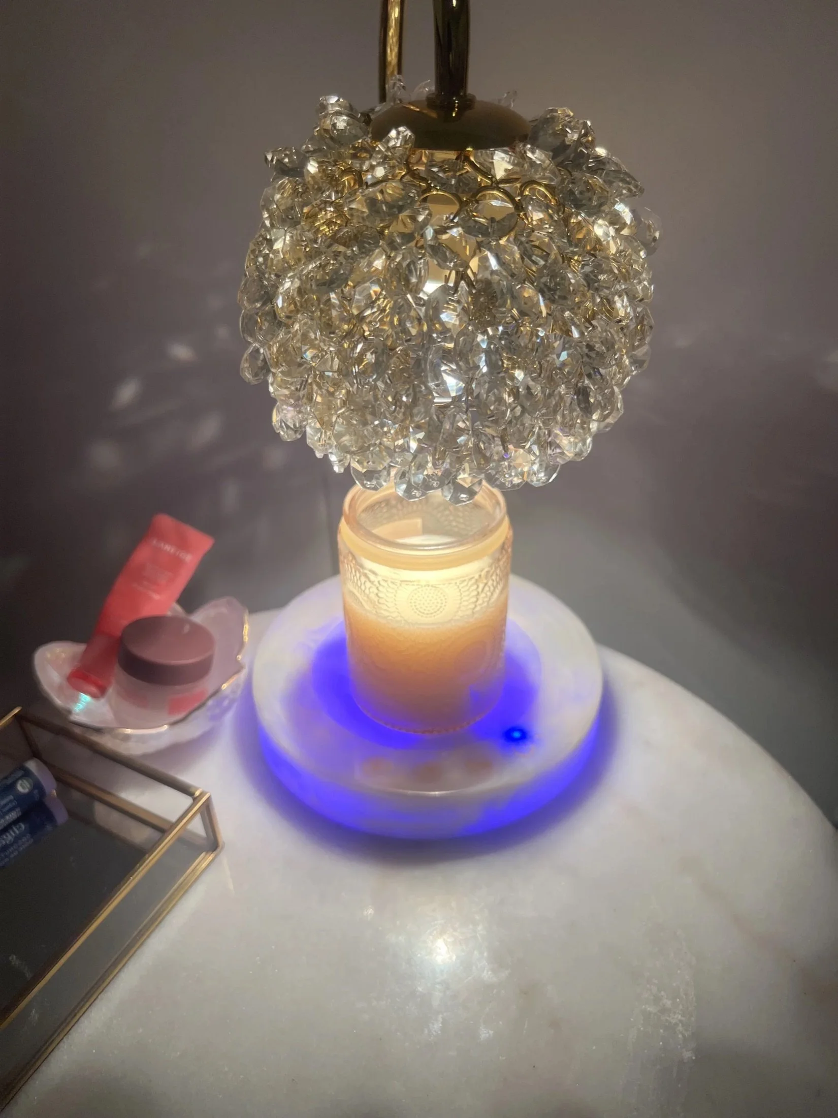 Lit candle under a crystal candle warmer lamp
