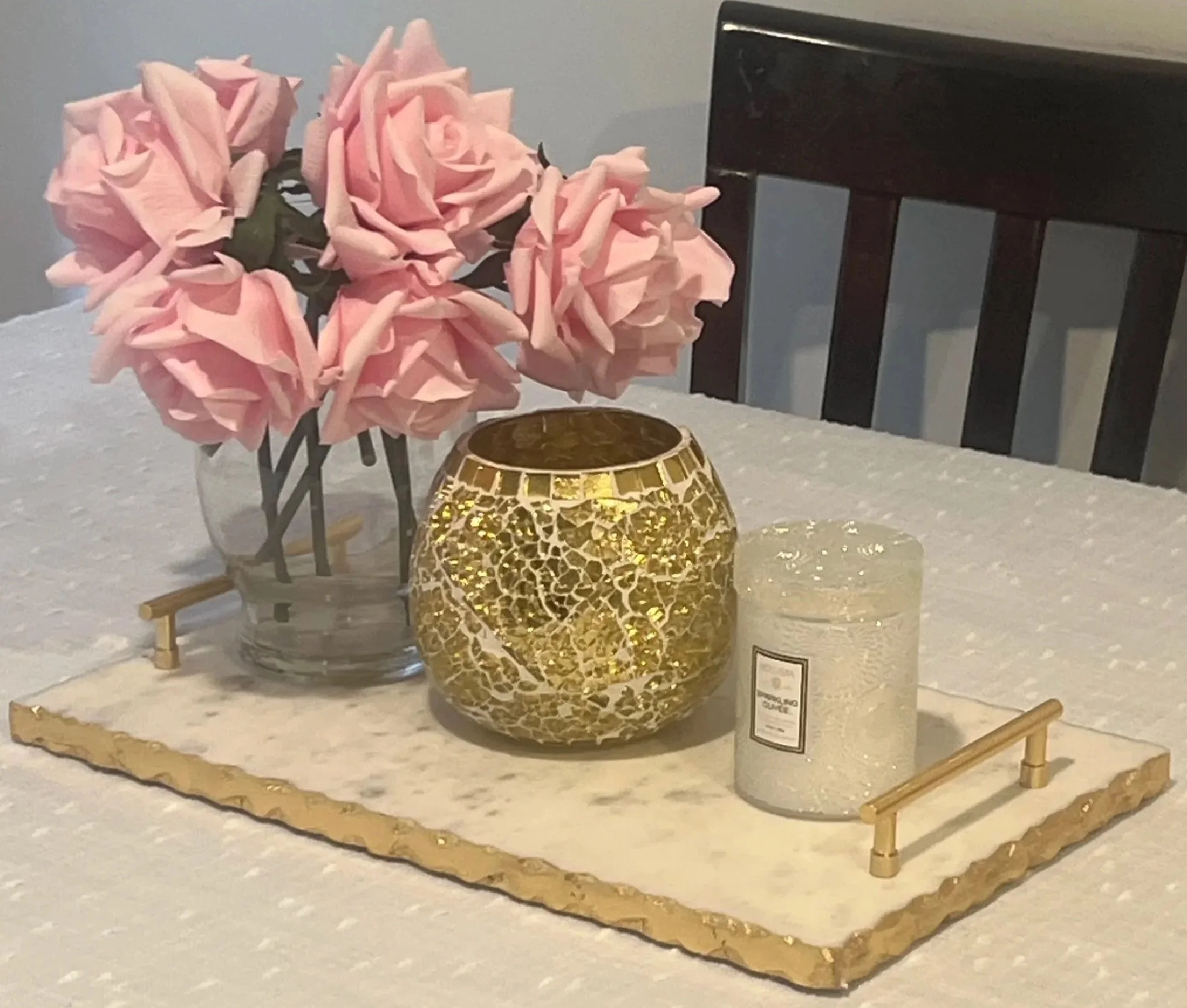Pink roses and a gold candle on a marble tray