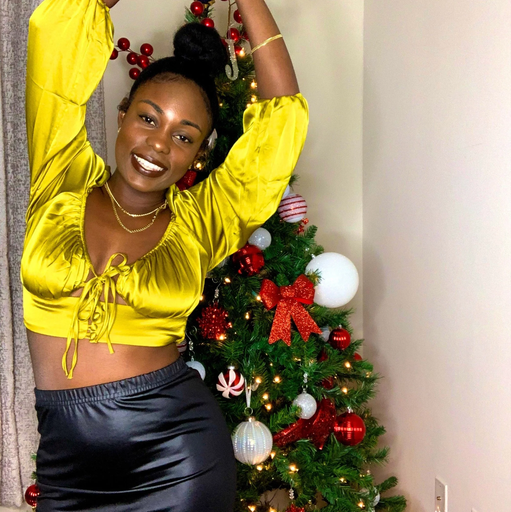 Brielle in a yellow top by a Christmas tree