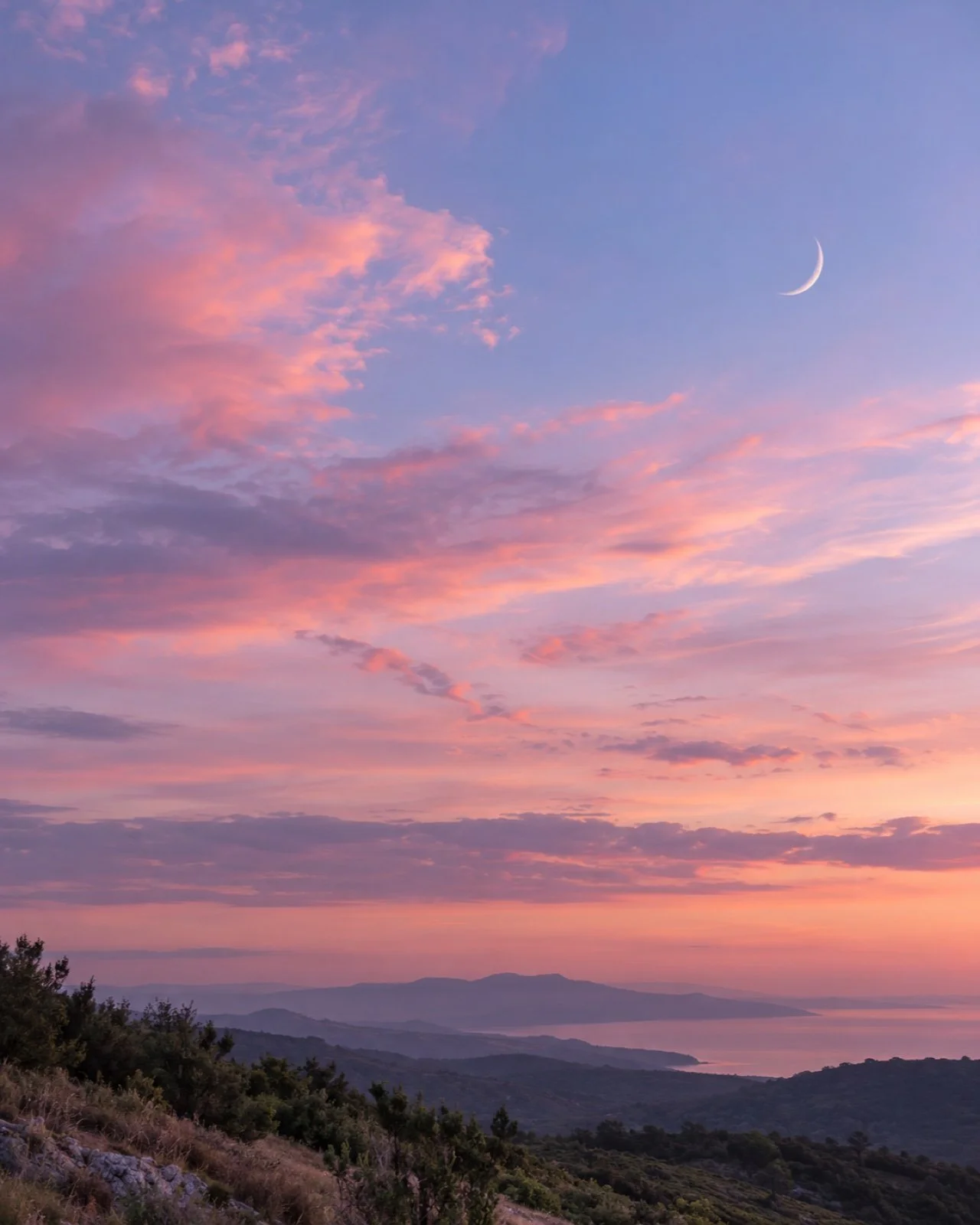 Crescent moon in a pink and lilac dusk sky