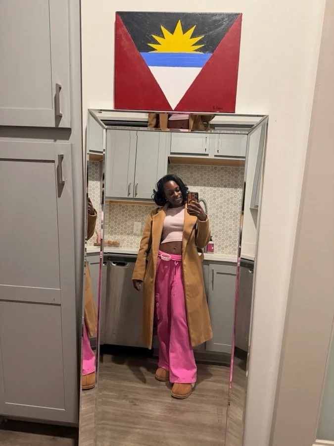Brielle in a camel coat and pink pants taking a mirror selfie