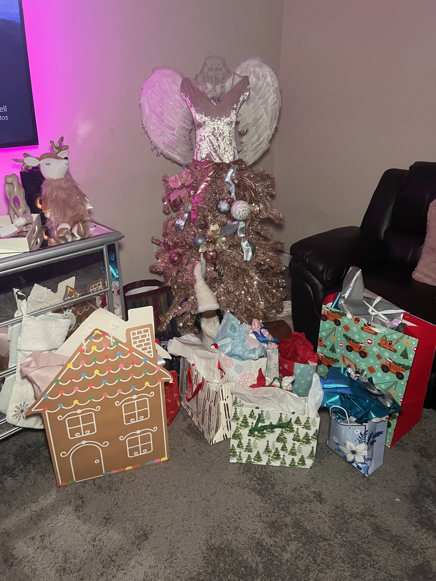 Gifts under a pink Christmas tree with a gingerbread house box
