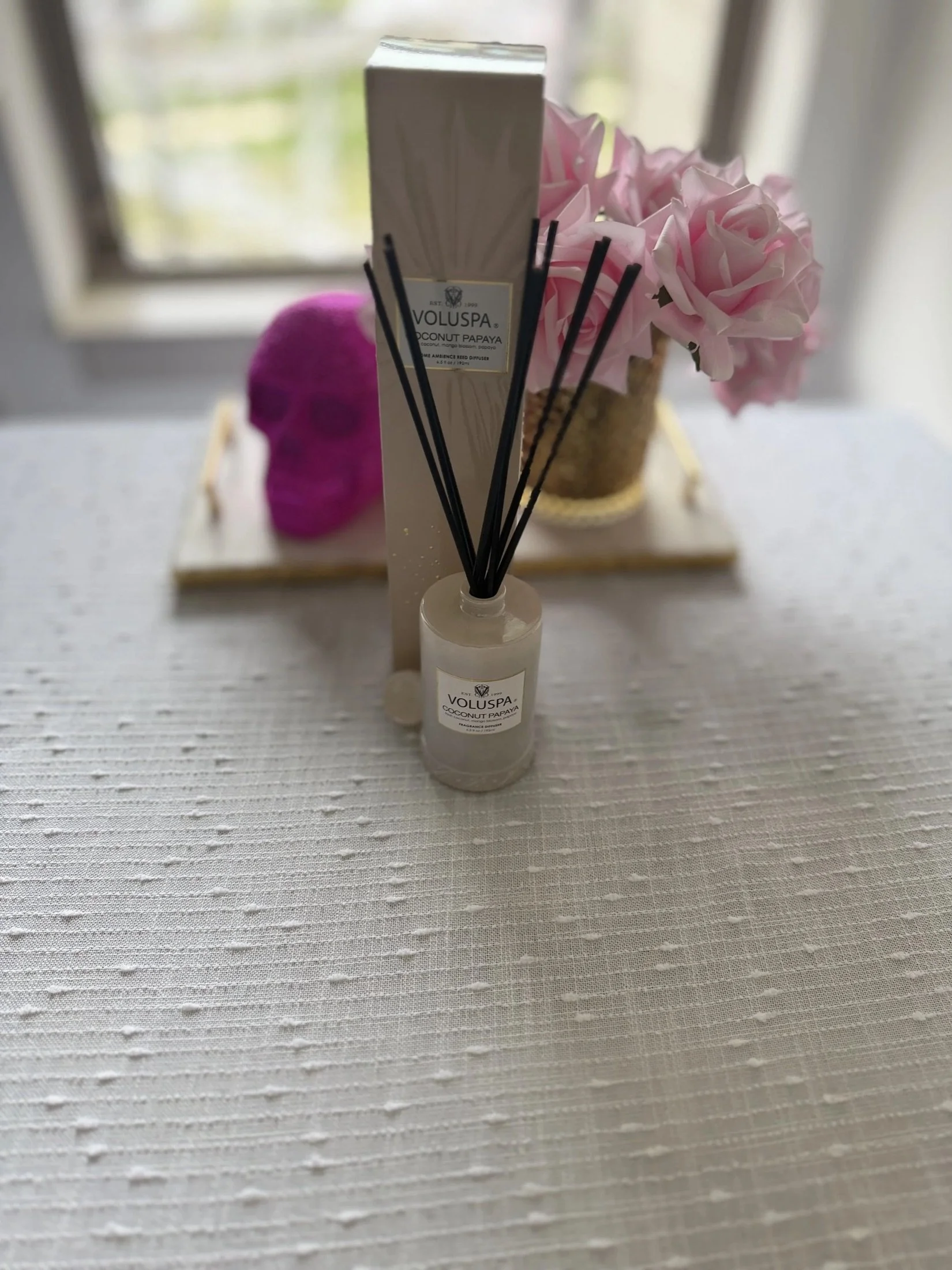Reed diffuser and pink roses on a cozy side table