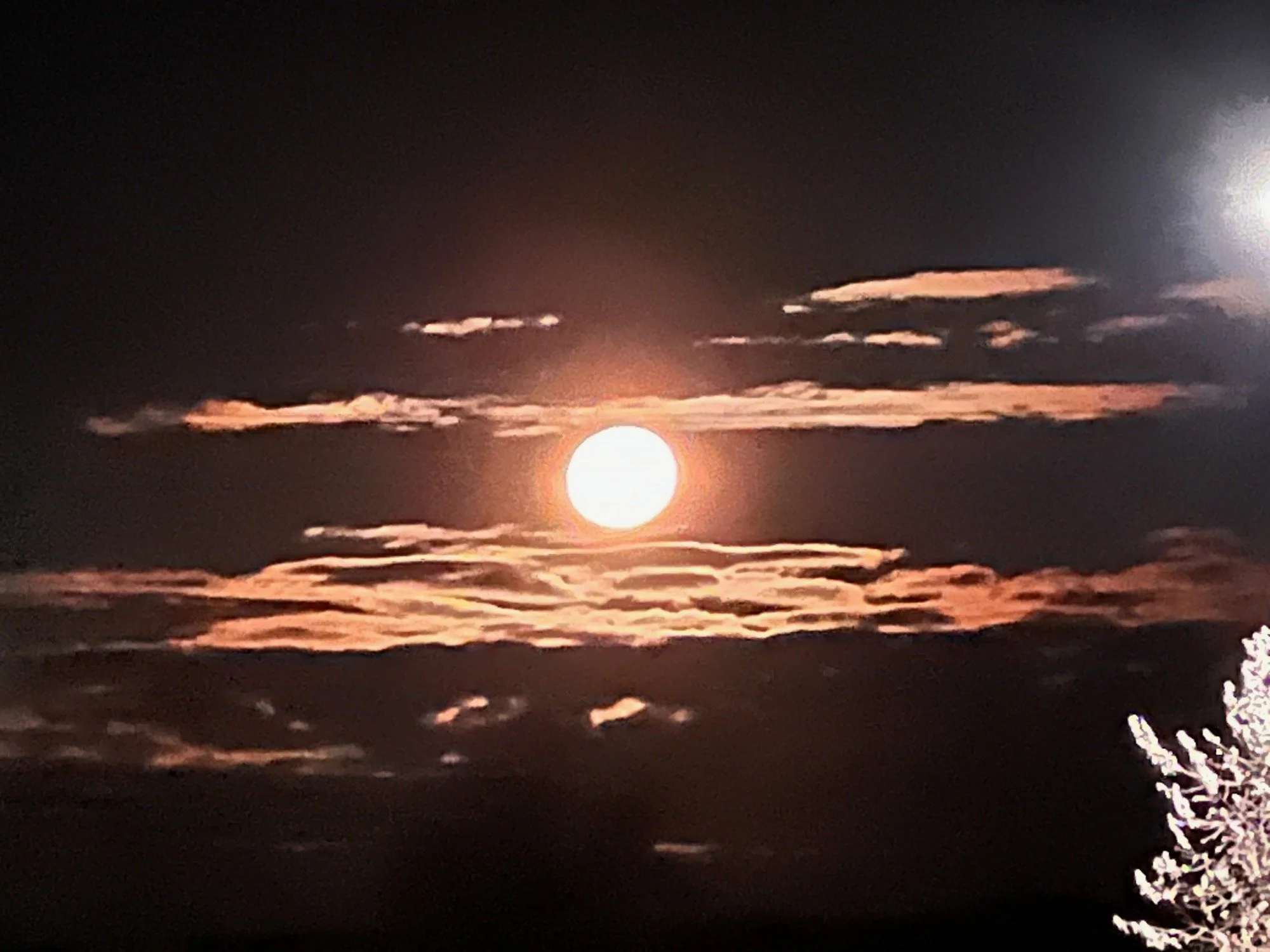 Full moon rising through glowing clouds