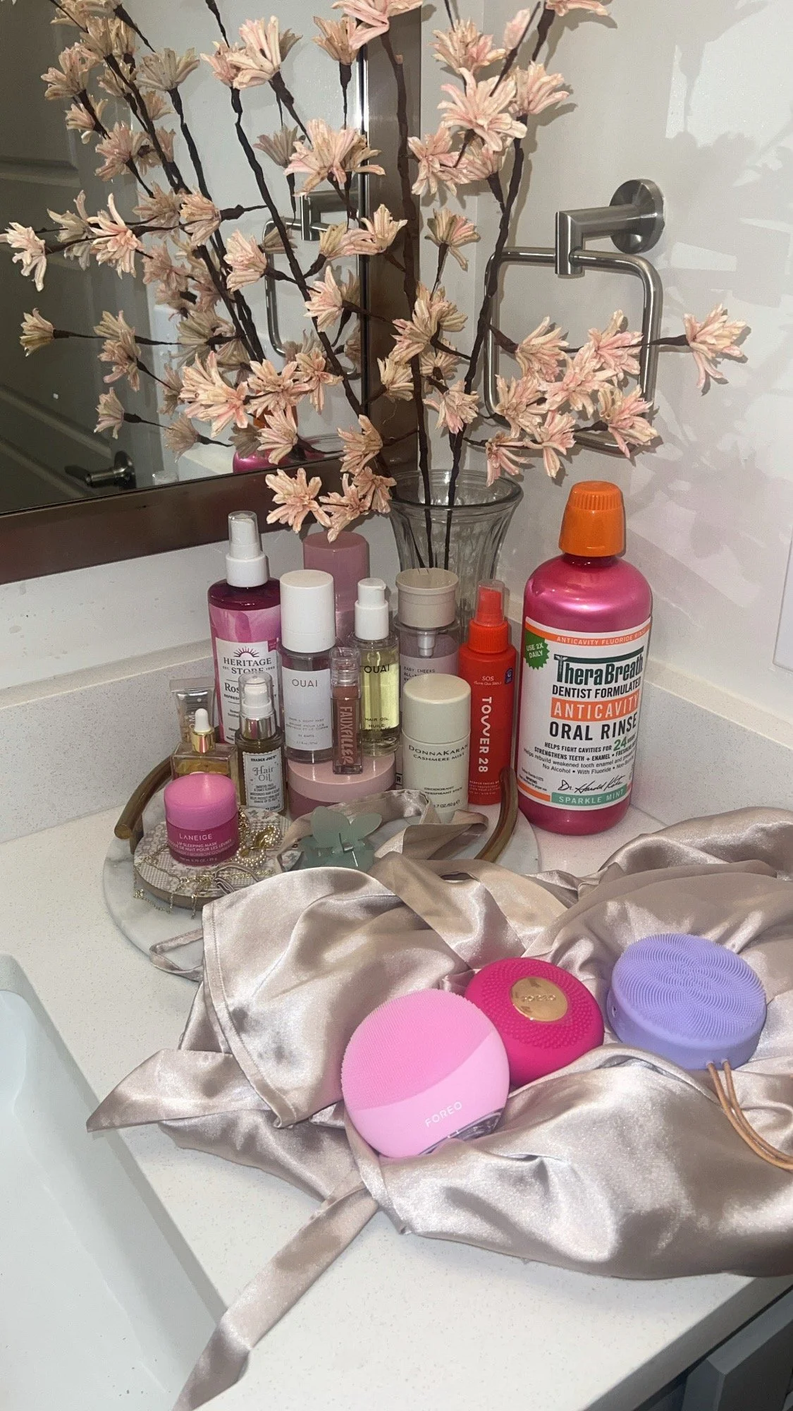 FOREO face brushes and skincare on satin with blossoms