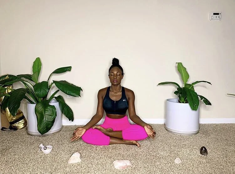Brielle meditating cross legged in pink yoga pants