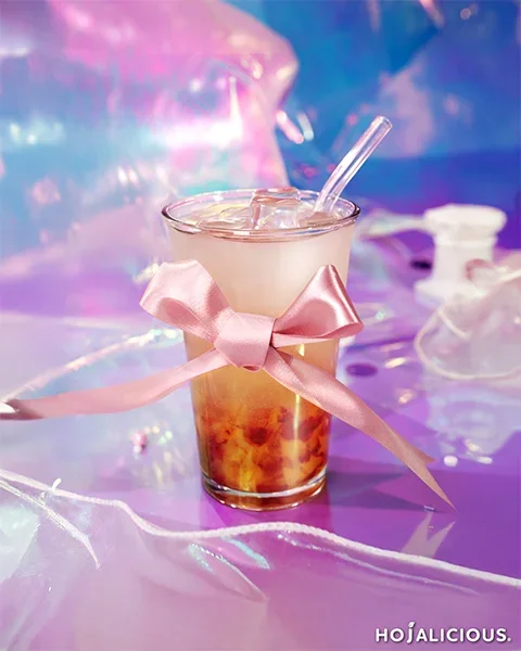Galaxy strawberry soda with mango star jelly topped with a pastel ribbon, photographed in a dreamy cosmic pink and purple setting.