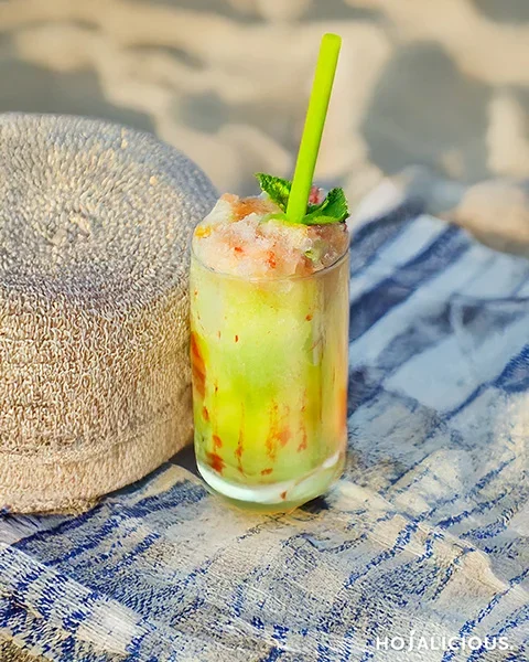 A layered green and orange slush drink with strawberry syrup drizzle — a playful green drink inspired by game world aesthetics.