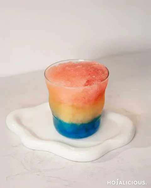 A colorful layered slush drink with strawberry, orange, and blue popping boba — a vibrant summer beverage perfect for café menus.