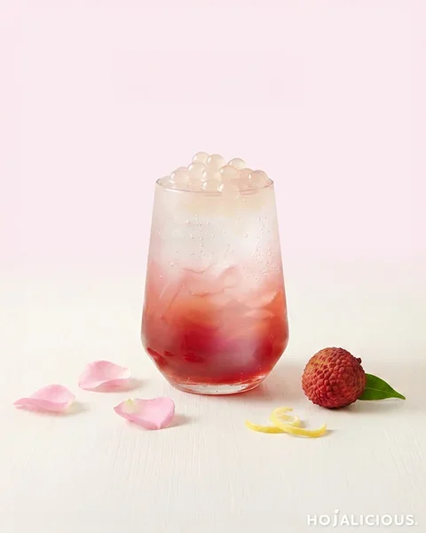 A Lychee Rose Sparkling Drink made with rose syrup, lychee syrup, lemon syrup, sparkling water, and lychee popping boba, creating a refreshing floral fruit beverage with vibrant color and texture.