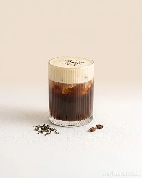 Milky Mist Jin Xuan Cold Brew Coffee made with cold brew coffee, Longan Honey Flavor Syrup, Jin Xuan tea cream foam, ice, and crushed tea leaves.