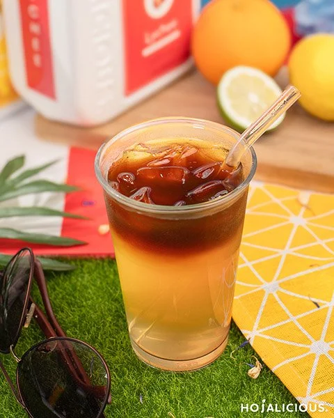 A dual-layered drink made with jasmine green tea, lychee, honey, and cold brew coffee, served over ice.